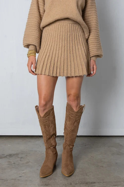 Falda plisada y suéter chic en un conjunto de mujer. Ideal para un look de moda elegante y cómodo de otoño.