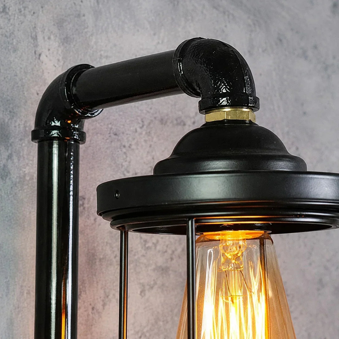 Aplique de pared negro con jaula metálica, diseño vintage industrial para luz decorativa en interiores.