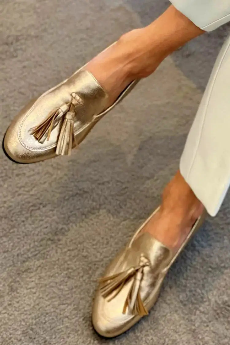 Mocasines dorados metalizados para mujer con borlas. Calzado elegante y cómodo, ideal para estilo casual.