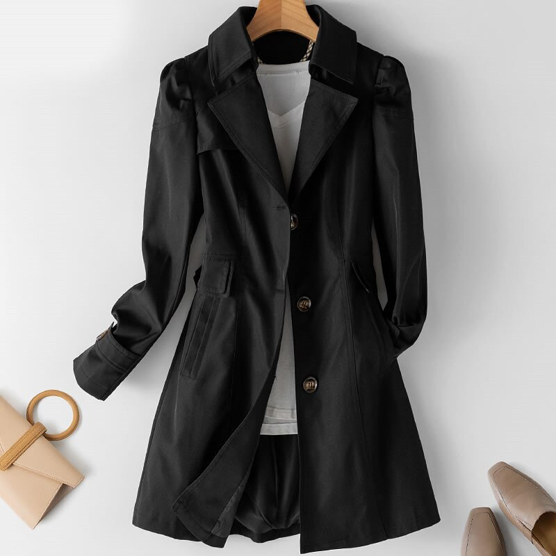 Gabardina femenina sofisticada con detalle de hombreras acolchadas y botón frontal. Prenda de vestir de moda.