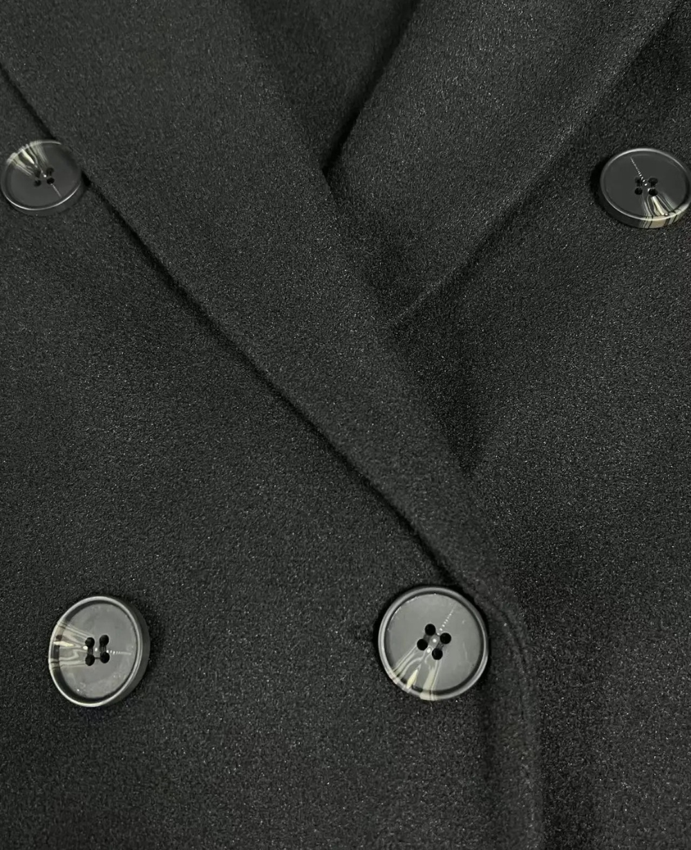 Detalle del tejido suave del abrigo largo, elegante, doble botonadura para mujer.