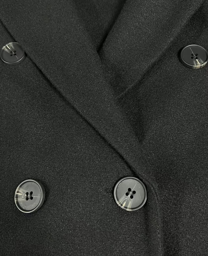 Detalle del tejido suave del abrigo largo, elegante, doble botonadura para mujer.