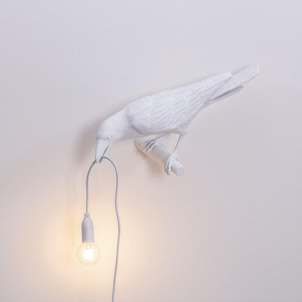 Ave de resina como lámpara de pared, diseño moderno y luz de ambiente única.