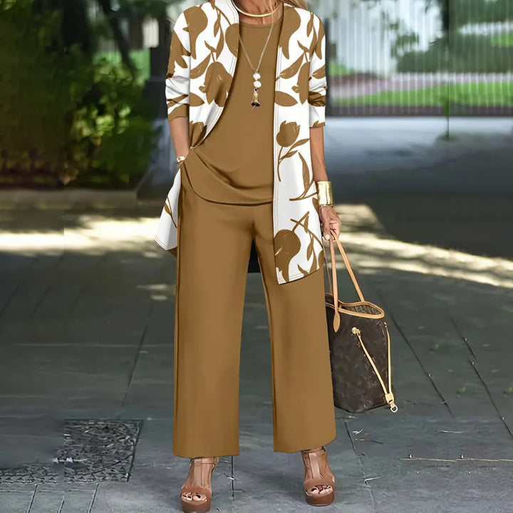 Mujer vistiendo conjunto de tres piezas: chaqueta floral, pantalón recto y blusa. Estilo versátil y moderno.