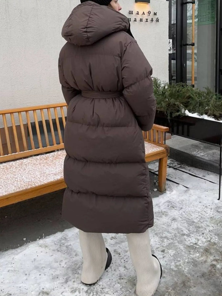 Abrigo de mujer acolchado, largo, con detalle de bolsillos y cinturón, funcionalidad y estilo.