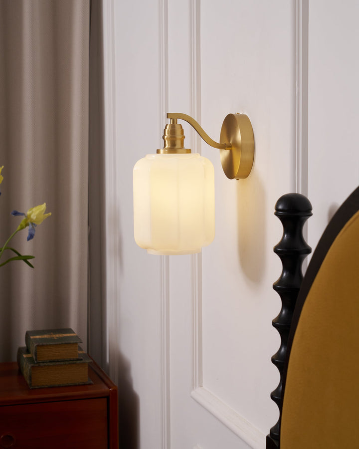 Lámpara compacta de pared con carcasa de latón y vidrio protector.