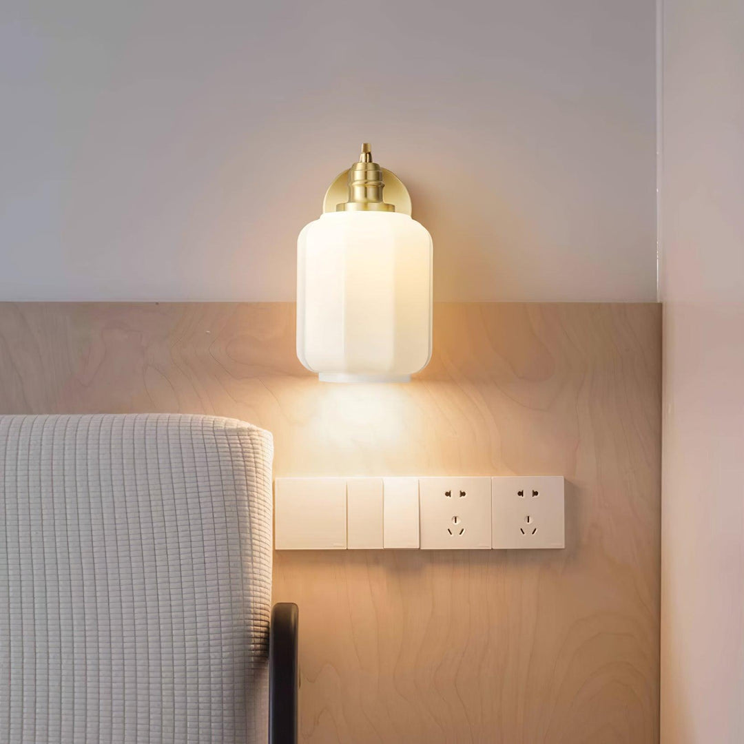 Iluminación compacta de pared con acabado en latón y pantalla de cristal.
