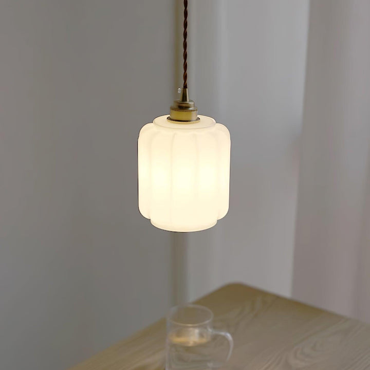 Iluminación moderna: lámpara colgante de cristal blanco y latón, diseño minimalista, luz ambiente.
