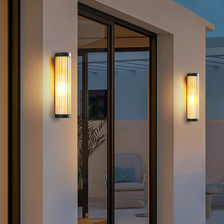 Aplique moderno cilíndrico instalado en pared, iluminación exterior funcional y decorativa.