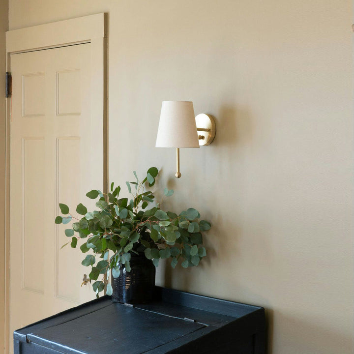 Lámpara de pared de latón con pantalla textil, ofrece luz cálida. Perfecta para decoración moderna.