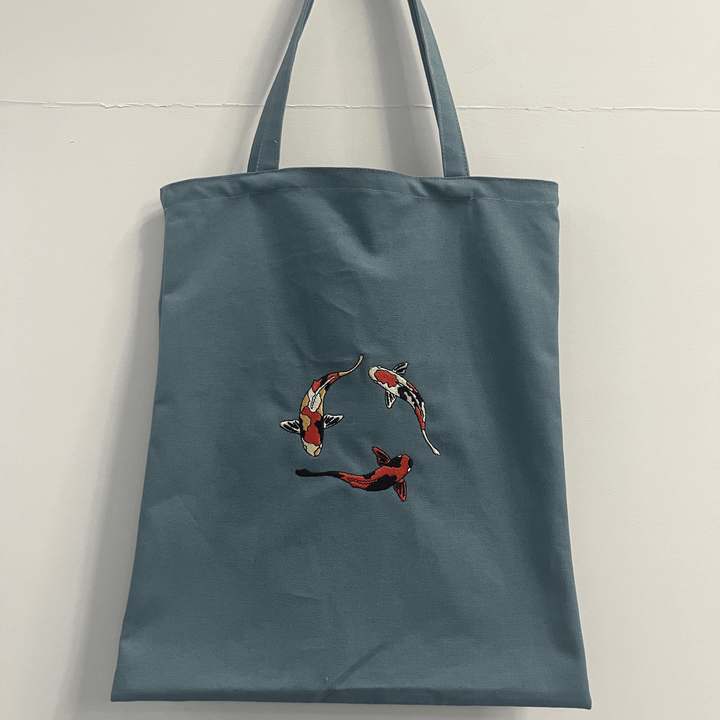 Bolso de hombro ecológico de lona para mujer con diseño de pez koi bordado, estilo minimalista y moda consciente.