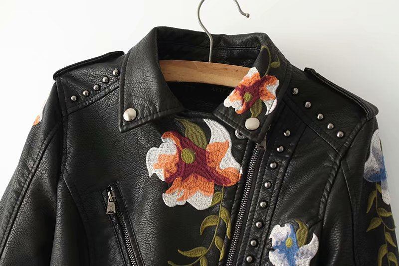 Bordado floral detallado y tachuelas en chaqueta biker de cuero sintético negra para mujer. Moda femenina.