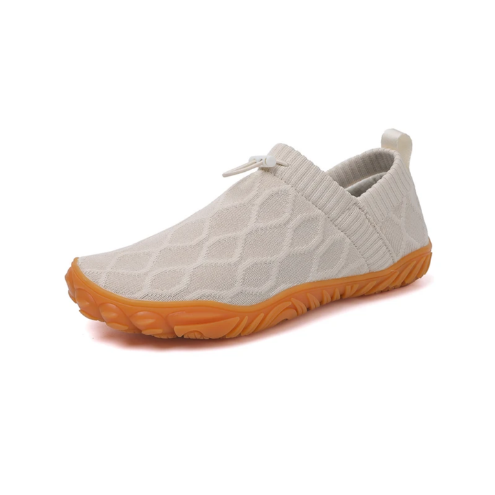 Persona con zapatillas barefoot de senderismo unisex en ruta de montaña. Calzado con puntera ancha y agarre superior.