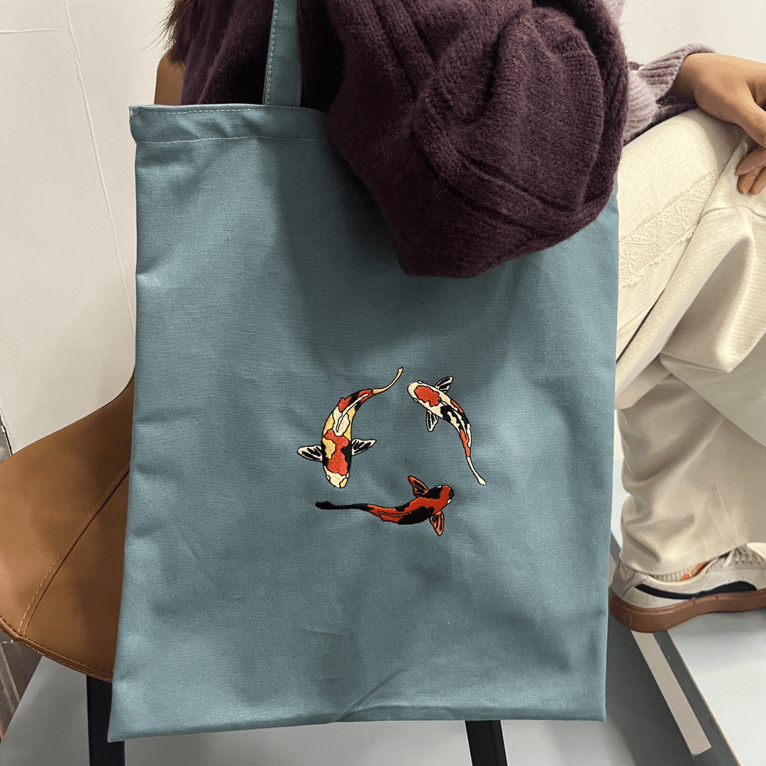 Bolso tote de lona resistente con diseño bordado de pez koi. Bolso de hombro para mujer, estilo minimalista y duradero.
