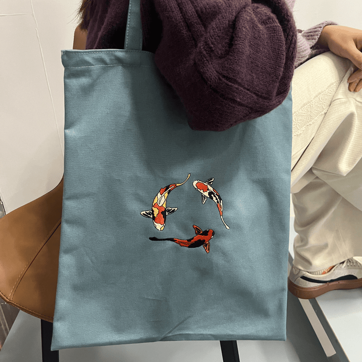 Bolso tote de lona resistente con diseño bordado de pez koi. Bolso de hombro para mujer, estilo minimalista y duradero.