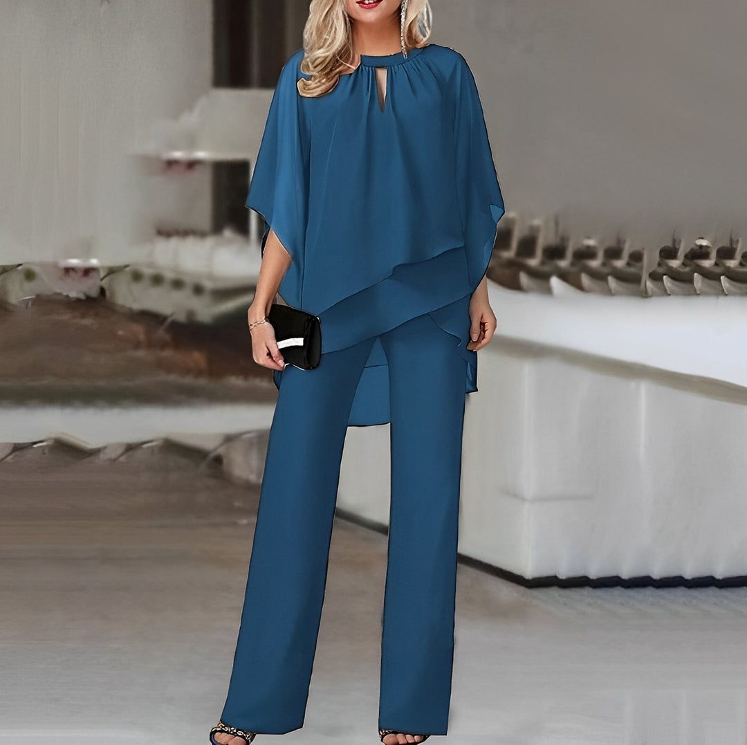 Modelo femenino con top capa chic y pantalón ancho sofisticado. Perfecto para invitada de boda o celebración.