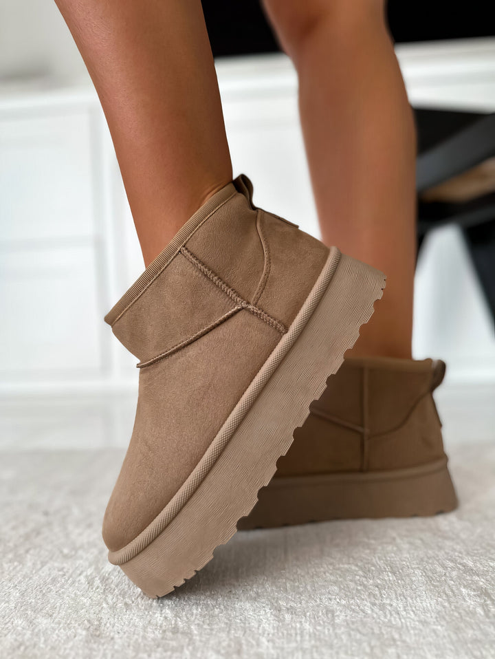 Detalle de la suela gruesa de plataforma en botines negros para mujer. Calzado urbano y con altura.