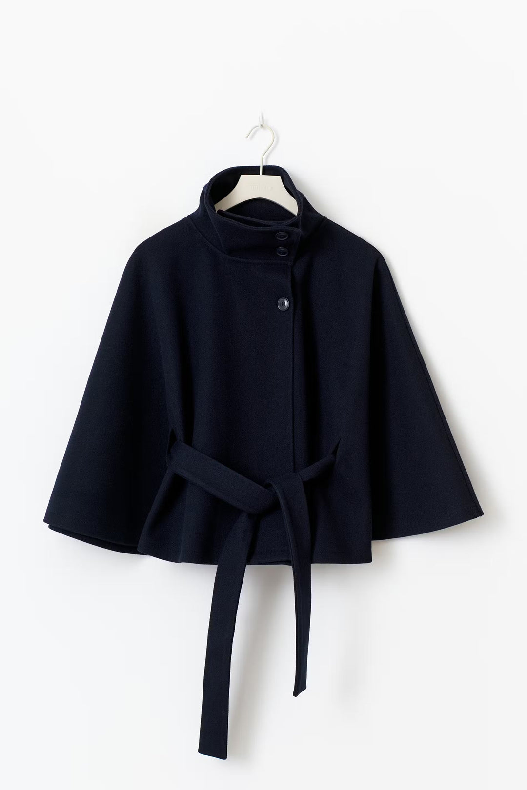 Mujer vistiendo chaqueta capa elegante con cuello alto y cinturón. Estilo moderno para el invierno.