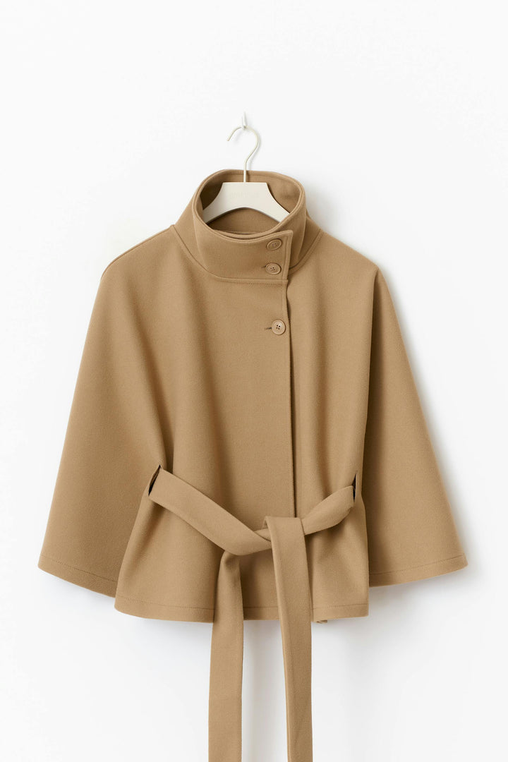 Chaqueta capa de mujer en color oscuro, con cuello alto y cinturón. Prenda elegante de invierno.