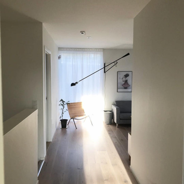 Lámpara de pared negra, estilo industrial, brazo ajustable para iluminación dirigida.
