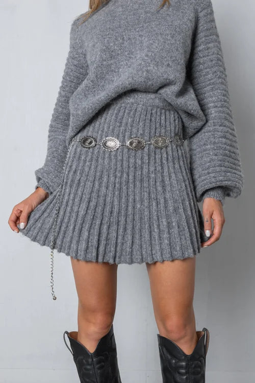 Conjunto de suéter de punto y falda plisada. Moda femenina elegante, cómoda y versátil para otoño-invierno.