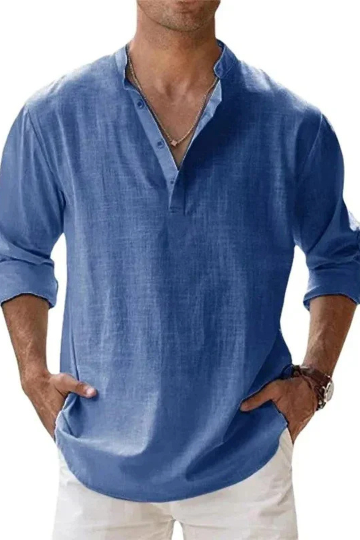 Hombre caminando en la playa con camisa Henley de lino beige, look relajado.