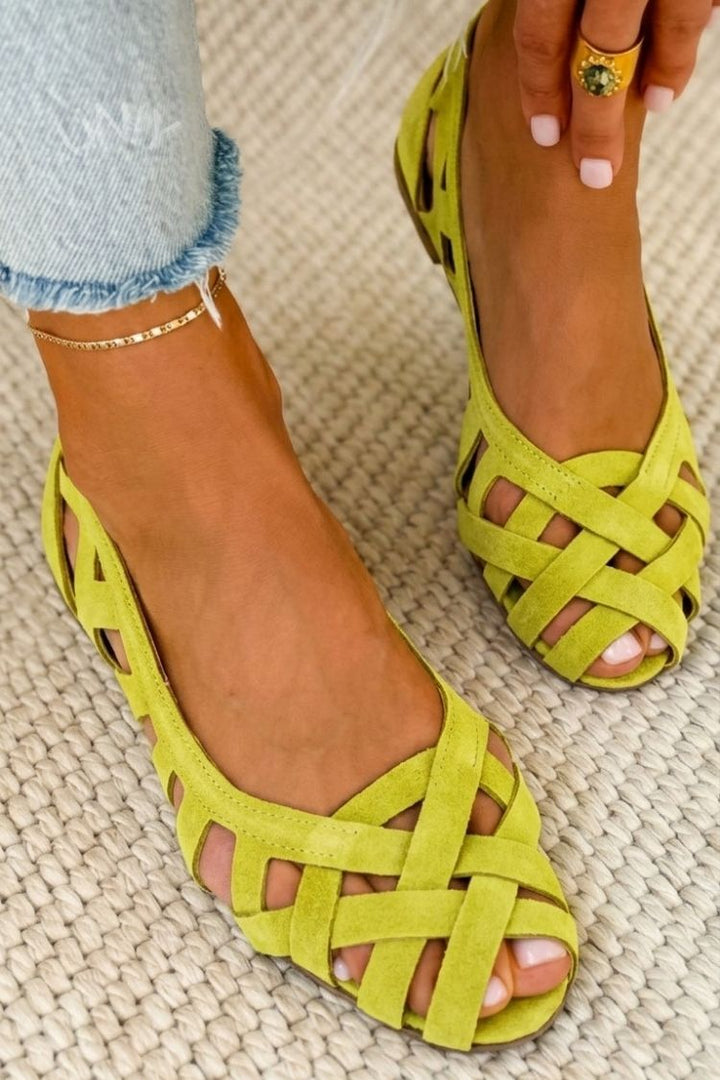 Pies de mujer con sandalias planas trenzadas de puntera abierta, perfectas para vacaciones de verano.