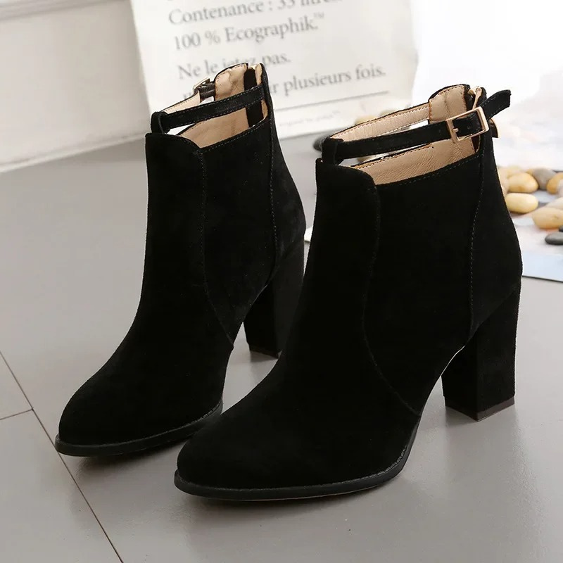 Botines negros de cuero sintético, tacón bloque robusto y hebilla decorativa.