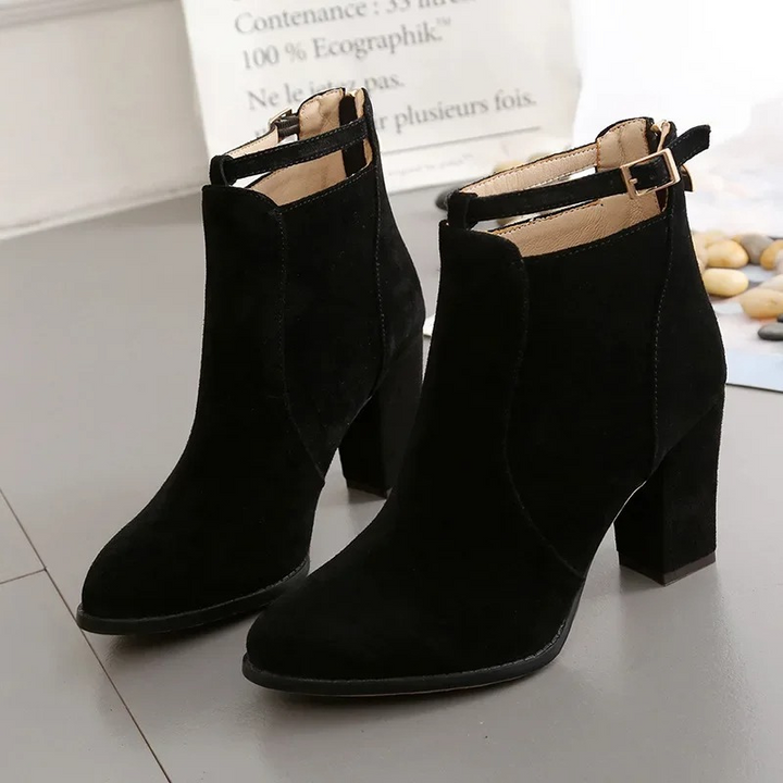 Botines negros de cuero sintético, tacón bloque robusto y hebilla decorativa.