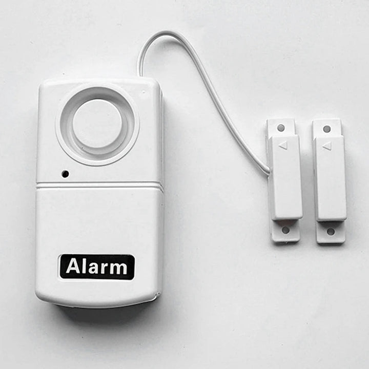 Sensor de alarma de seguridad portátil instalado en puerta. Protege tu hogar con fácil instalación y alerta inmediata.