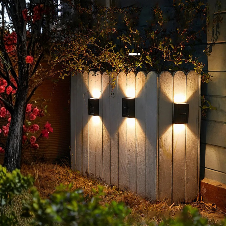 Varias luces solares LED de pared iluminando un sendero en el jardín, efecto arriba/abajo en exterior.