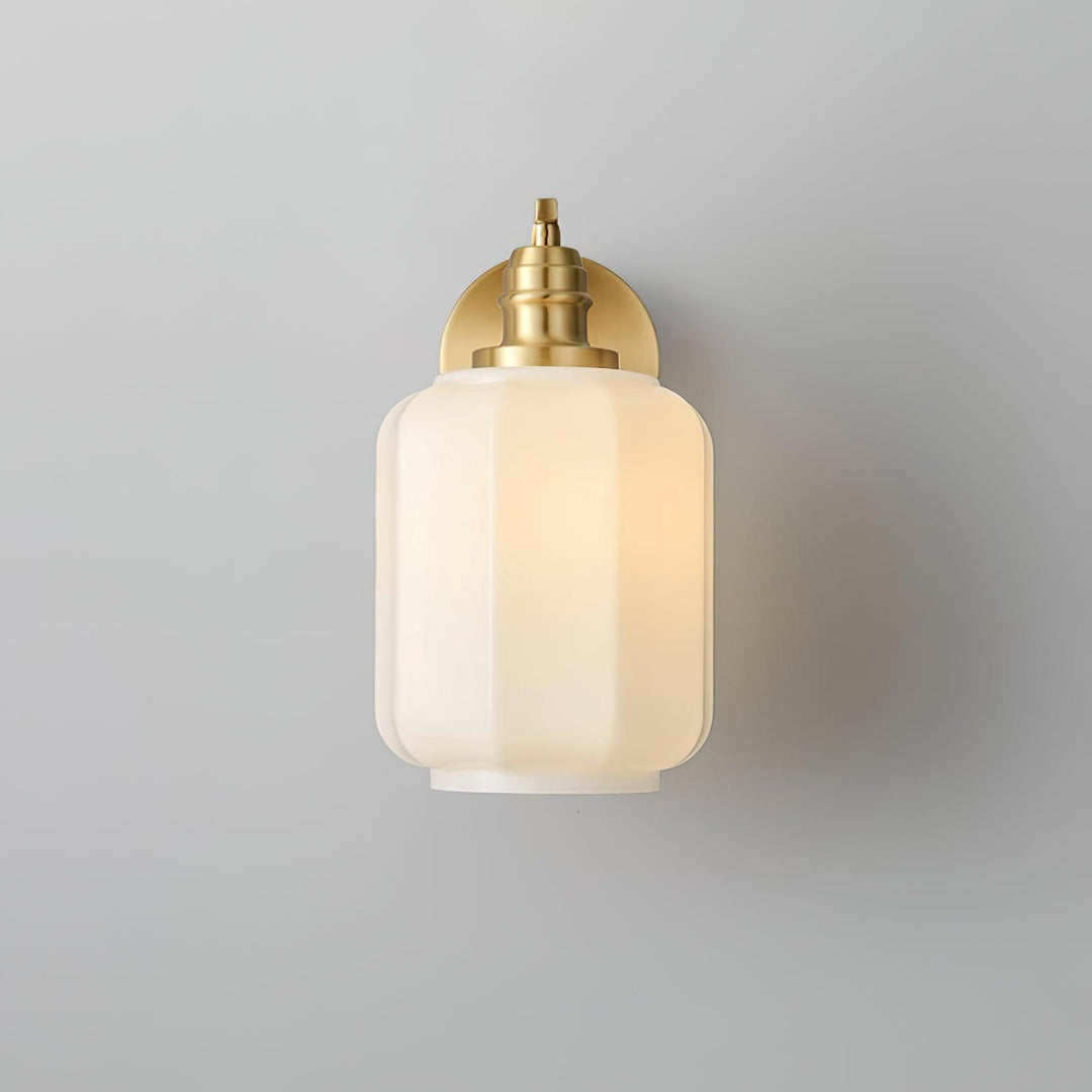Lámpara de pared compacta de latón y cristal, ideal para un toque industrial.