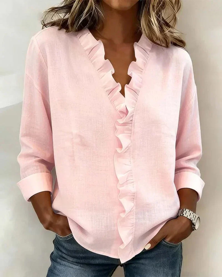Moderna blusa rosa para mujer con volantes decorativos, escote en V y mangas largas fluidas.