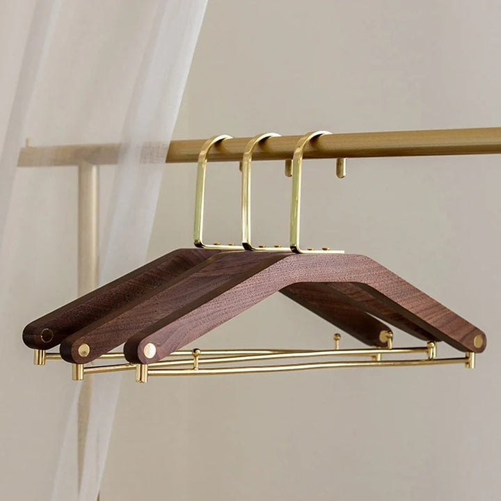 Perchas de madera de nogal macizo con gancho de latón, diseño elegante para organizar ropa en armario del hogar.