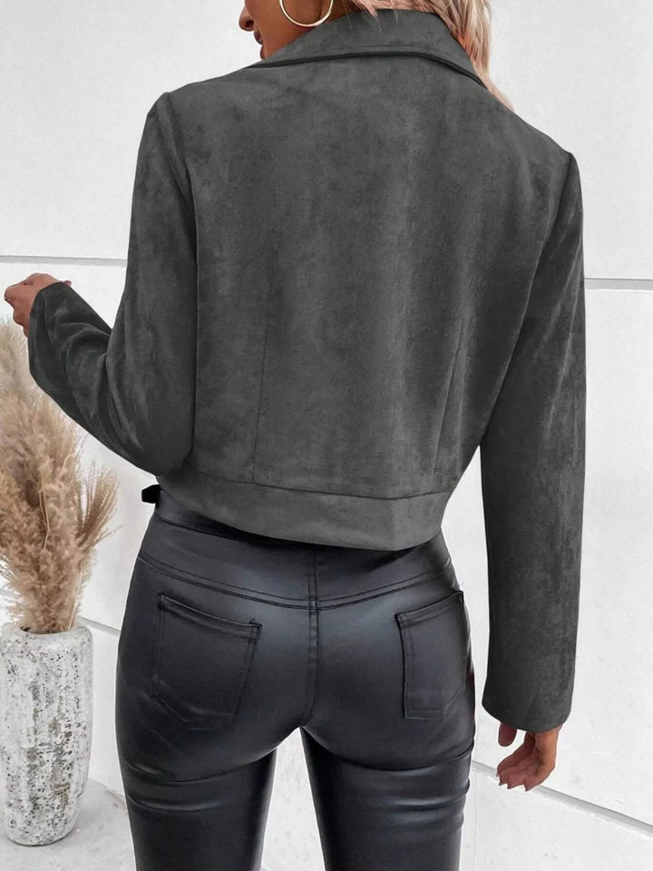 Detalle de la cremallera y bolsillos de la chaqueta corta de mujer, estilo chic y funcional.