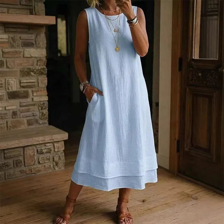 Vestido midi de verano, sin mangas, con bolsillos y un volante chic. Diseño cómodo y fluido de poliéster.