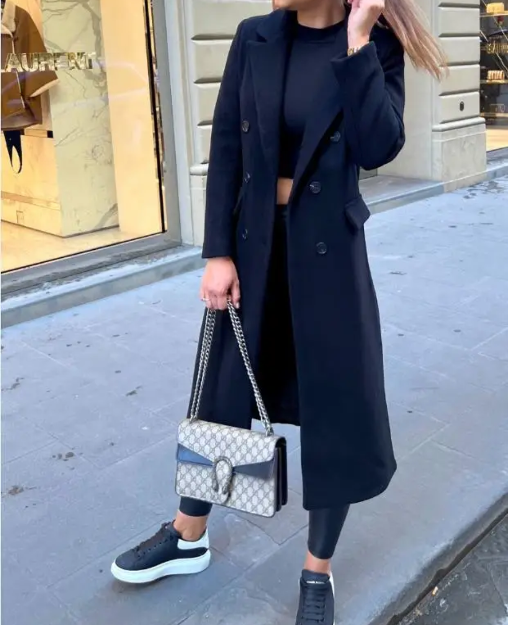 Detalle frontal: abrigo doble botonadura, solapas amplias, estilo clásico para mujer.