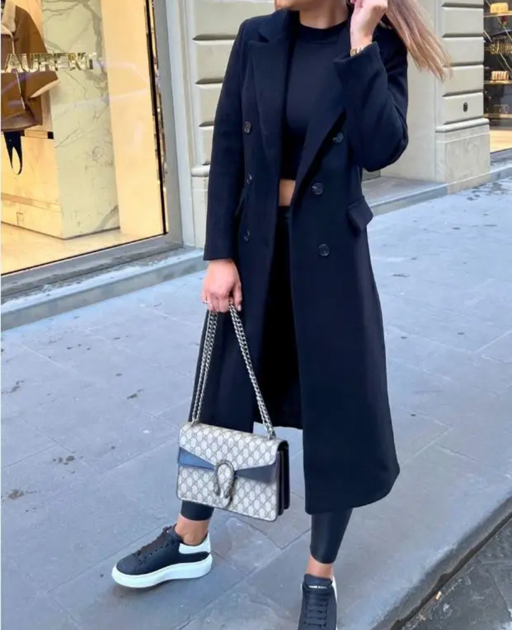 Detalle frontal: abrigo doble botonadura, solapas amplias, estilo clásico para mujer.