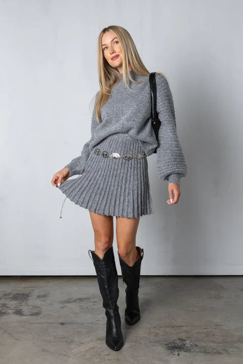 Conjunto de suéter de punto y falda plisada fluida. Moda femenina elegante y cómoda para temporadas frías.