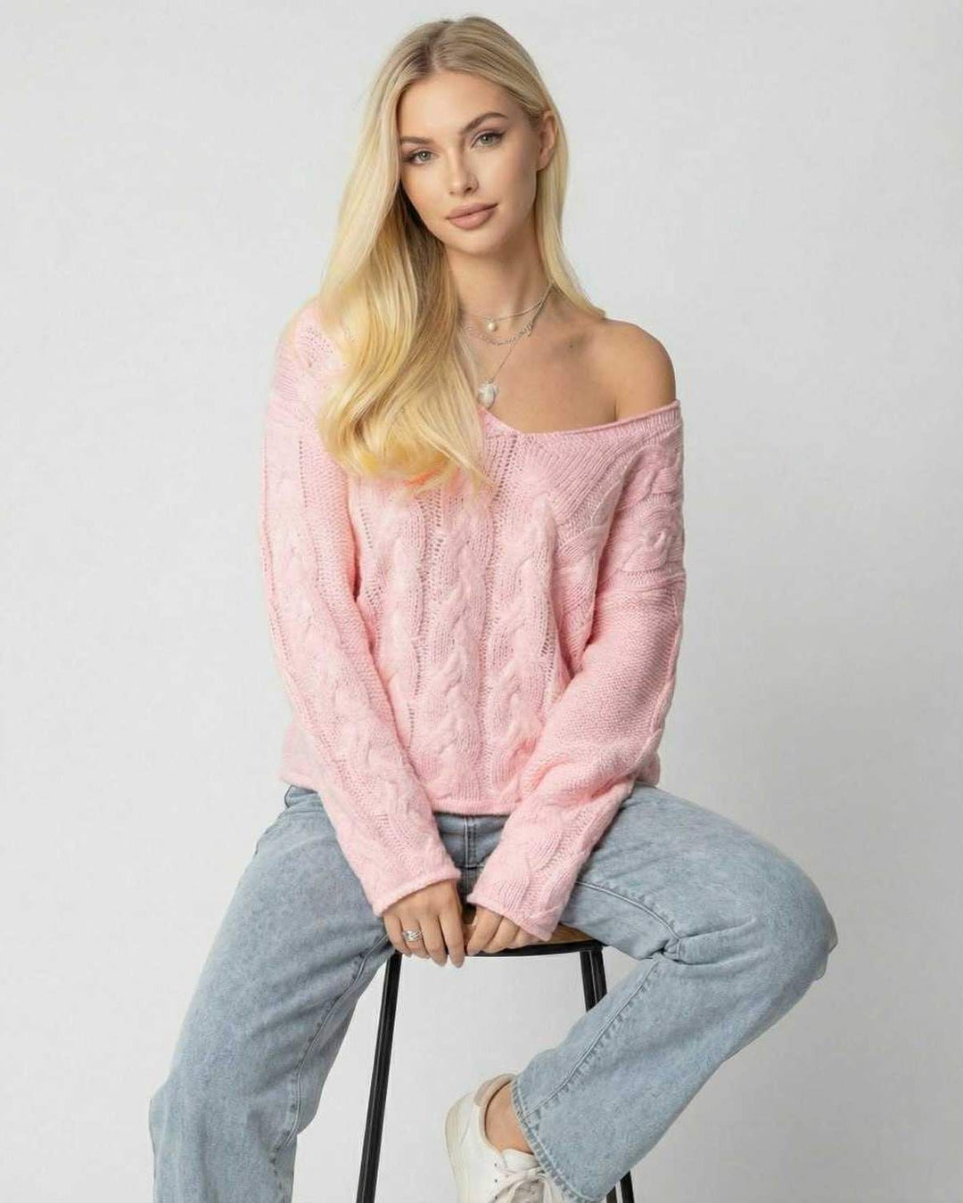 Modelo con suéter rosa de cuello V, manga larga, ajuste relajado, creando un look elegante y cómodo de invierno.