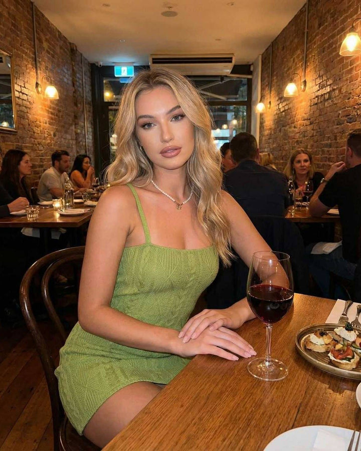 Mujer luciendo vestido mini verde ajustado con espalda abierta. Atuendo chic para fiesta o cóctel de verano.