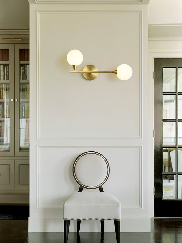 Luminaria de pared en latón con 2 globos de cristal blanco. Ideal para un toque transicional.