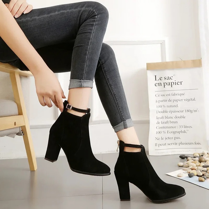 Calzado femenino elegante: botines negros con tacón bloque y detalle de hebilla.