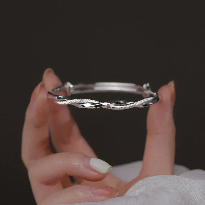 Pulsera de plata Elara trenzada en muñeca femenina, joya minimalista perfecta para cualquier ocasión.