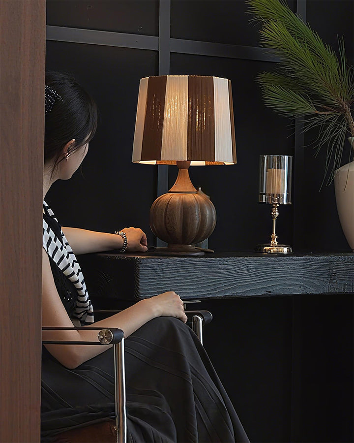 Estilosa lámpara de mesa con rayas verticales y base de madera, perfecta para un ambiente moderno.