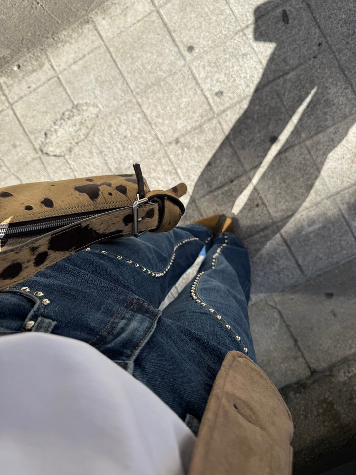 Estilosos vaqueros denim para mujer, corte wide leg y diseño con tachuelas brillantes en los laterales.