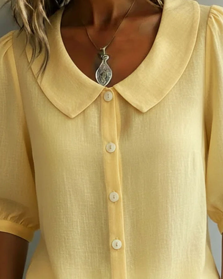 Blusa femenina blanca, cuello Peter Pan y manga fluida. Diseño versátil y elegante para cualquier ocasión.