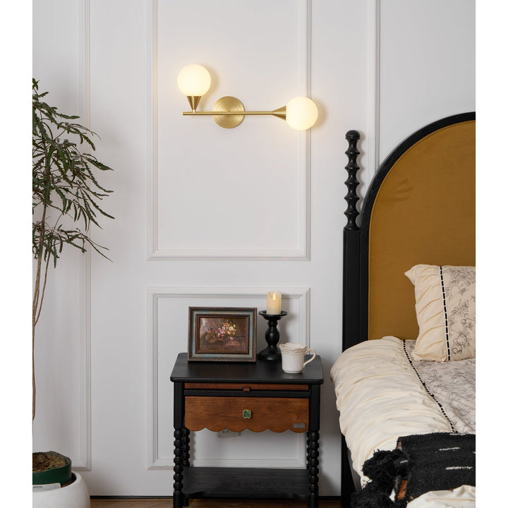 Lámpara de pared con 2 globos de cristal blanco, estructura de latón. Iluminación sofisticada.