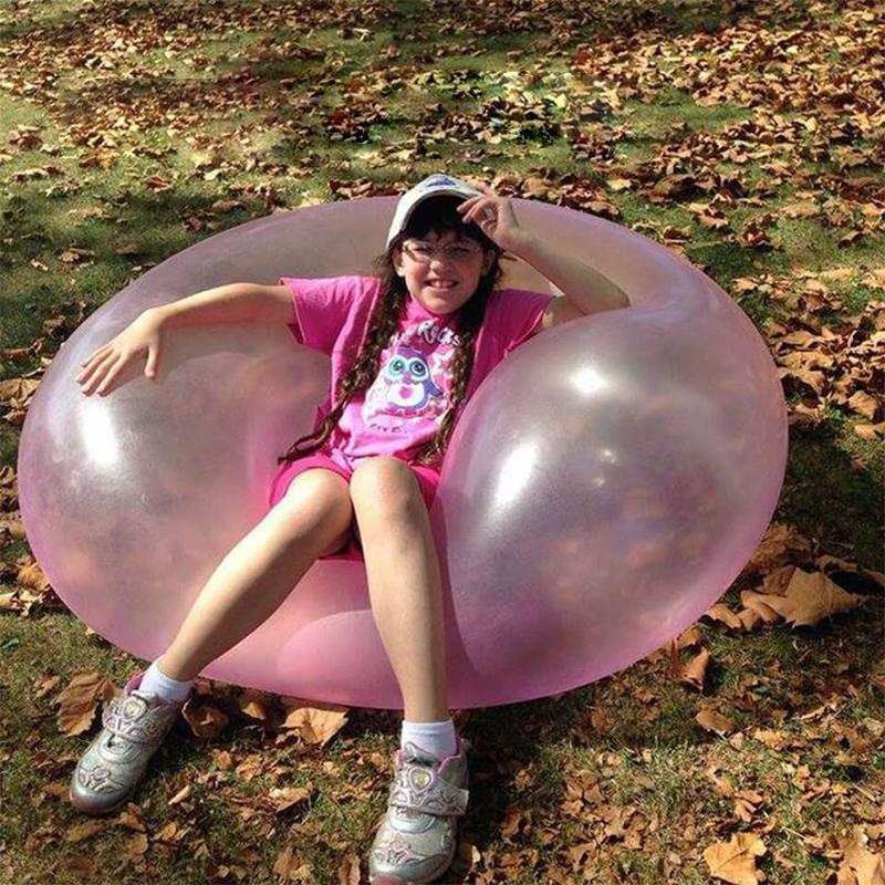 Grupo de niños jugando con globo bubble gigante. Juguete inflable resistente que promueve la diversión compartida.