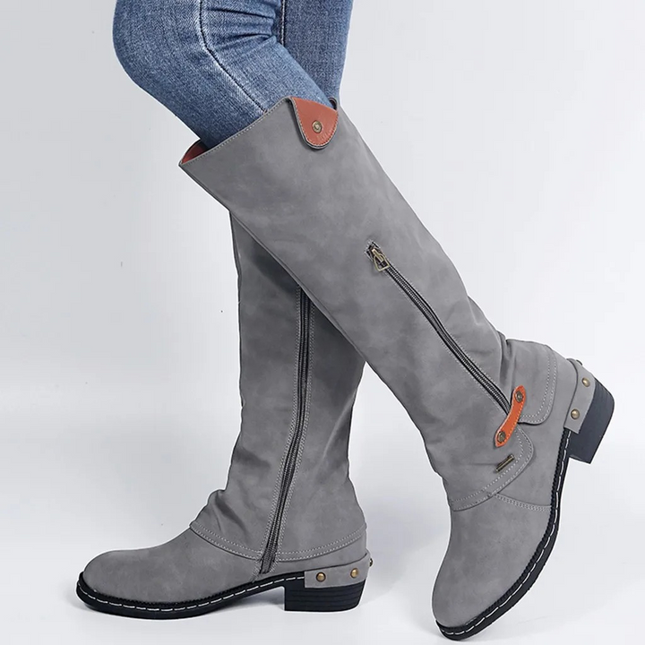 Primer plano de botas altas elegantes para mujer con botón metálico. Detalle sofisticado de calzado.